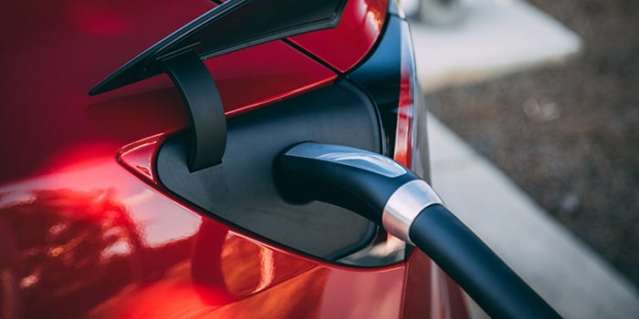 red electric vehicle plugged into charging station